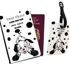 Puede incluir: Portapasaporte blanco con una ilustración de un cachorro dálmata en blanco y negro. El texto "Your Name" y "Look for the good spots in life" está impreso en el portapasaporte. También se muestra una etiqueta de equipaje a juego con el mismo diseño.