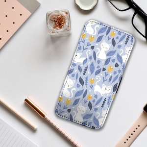 May include: A blue phone case with a white cat and flower pattern. The case has a white border.
