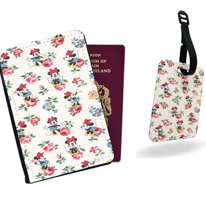 May include: A passport holder and luggage tag featuring a repeating pattern of Minnie Mouse characters and floral designs on a cream background. The passport holder is open, revealing a burgundy passport. The luggage tag has a black strap.
