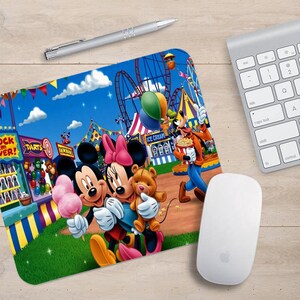 Puede incluir: Un ratón de ordenador colorido con Mickey Mouse y Minnie Mouse en un carnaval. El ratón de ordenador tiene un fondo de cielo azul con una noria, una tienda de campaña y otras atracciones de carnaval. Mickey y Minnie están sosteniendo algodón de azúcar y un oso de peluche.