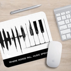 May include: A white mouse mat with a black and white piano keyboard and a sound wave graphic. The text "WHERE WORDS FAIL, MUSIC SPEAKS" is printed at the bottom of the mouse mat.