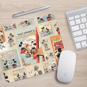 May include: A mouse mat featuring a vintage comic book design with multiple panels of Mickey Mouse in various poses. The background is a light beige with red, blue, and yellow accents. The text "WALT DISNEY'S MICKEY MOUSE" is featured in a red banner at the top of the mouse mat.