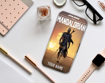 Può includere: Una custodia per telefono in pelle marrone con una grafica di un personaggio mandaloriano della serie televisiva Star Wars "The Mandalorian". Il testo "Star Wars - The Mandalorian" è stampato sulla custodia. Il testo "Your Name" è stampato nella parte inferiore della custodia.