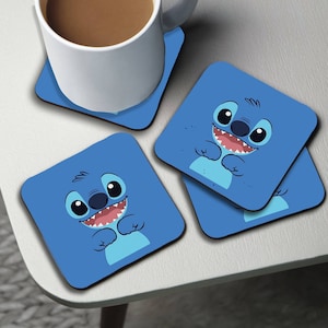 Könnte beinhalten: Set mit vier blauen quadratischen Untersetzern mit einem Cartoon-Bild von Stitch aus dem Disney-Film Lilo & Stitch. Jeder Untersetzer hat einen weißen Rand.