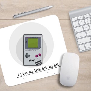 May include: A white mouse pad with a gray Game Boy illustration and the text "I Live my life bit by bit".