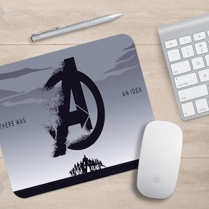 Könnte beinhalten: Eine graue Mausmatte mit einem Schwarzweißbild des Avengers-Logos und dem Text "THERE WAS AN IDEA".