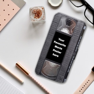 May include: A gray and black VHS tape style phone case with the text "Your Favourite Movie Poster here".