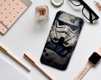 Può includere: Una custodia per telefono nera e bianca con un design di Stormtrooper di Star Wars. L'elmetto dello Stormtrooper è l'elemento principale del design.