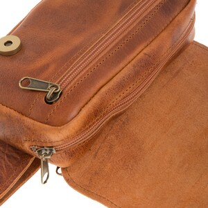 Peut inclure: Une banane en cuir marron avec une poche zipp&eacute;e et une fermeture &agrave; pression. La banane a une boucle de ceinture et un tirette de fermeture &eacute;clair.