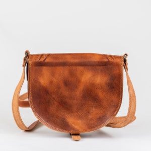 May include: A brown leather satchel bag with a flap closure and a long adjustable strap. The bag has a distressed look and is made of high-quality leather.