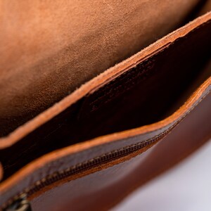 Puede incluir: El interior de un bolso de cuero marr&oacute;n con cierre de cremallera. El bolso est&aacute; forrado con un tejido marr&oacute;n suave.