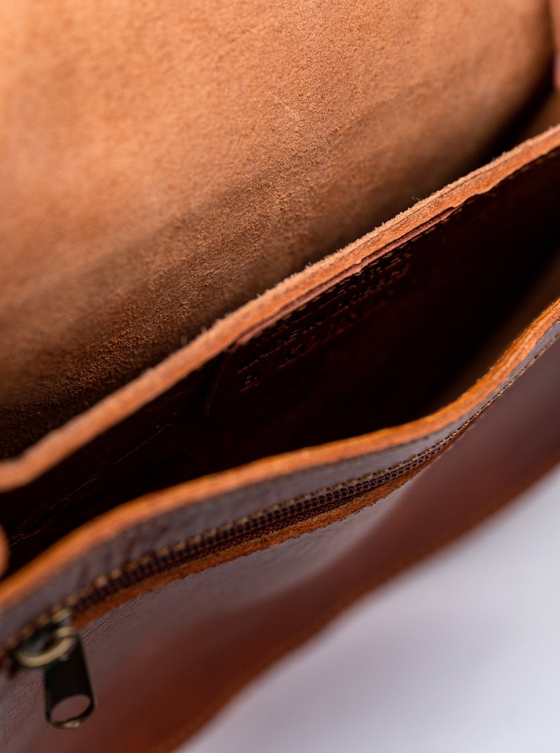 Puede incluir: El interior de un bolso de cuero marr&oacute;n con cierre de cremallera. El bolso est&aacute; forrado con un tejido marr&oacute;n suave.