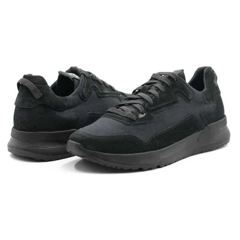 Puede incluir: Un par de zapatillas negras con puntera de ante y parte superior de lona. Las zapatillas tienen una suela blanca y un cord&oacute;n negro.