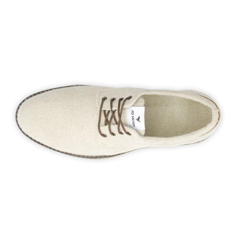 May include: A pair of off-white canvas lace-up shoes with brown laces and a brown rubber sole. The shoes have a label on the side that says "JO HEMP".