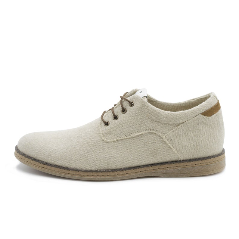 May include: Beige canvas lace-up shoes with a brown leather trim and a brown rubber sole.