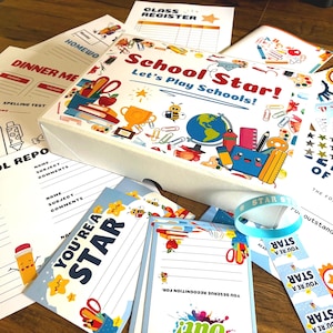 May include: A School Star! Let's Play Schools! box set featuring colourful school-themed illustrations including a globe, trophy, and books. The set includes various printed paper forms like a class register, school report, and certificates of achievement.