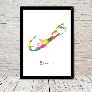 May include: A framed print displaying a colourful watercolour map of Bermuda. The map, in shades of yellow, pink, green, and blue, is set against a white backdrop. The word "Bermuda" is written beneath the map in a simple font.