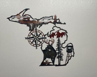 May include: Metal wall art depicting the outline of Michigan, featuring a compass, deer, lighthouse, and boat. The artwork is in shades of brown and black, with red accents on the leaves.