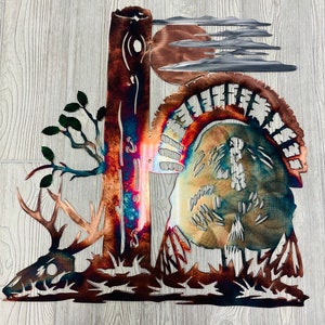 Könnte beinhalten: Metallische Wandkunst, die einen Hirschschädel, einen Baum und einen Truthahn mit einem vollen Federfächer darstellt. Das Kunstwerk ist in Braun-, Kupfer- und Blautönen bemalt.