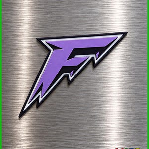 May include: A stylized letter F emblem featuring a purple center with black and white layered borders. The design has sharp, angular edges and a pointed tail. In the bottom right corner, the text WARP ZONE is printed in a colorful, pixelated font.