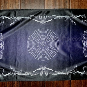 May include: A rectangular black and blue tapestry with a white labyrinth design in the center. The tapestry has a white border with abstract designs. The text "Impressions LLC" is visible on the right side.
