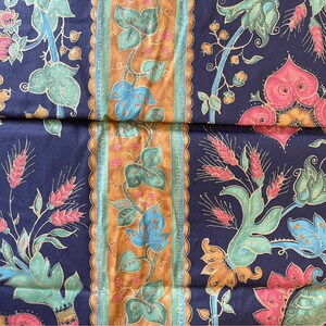 May include: A dark blue fabric with a repeating pattern of gold, green, and pink floral designs. The fabric has a vintage feel and would be perfect for upholstery or quilting.