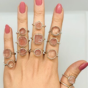 Peut inclure: Un mannequin de main portant une variété de bagues serties de pierres précieuses en quartz rose rose dans de l'argent.