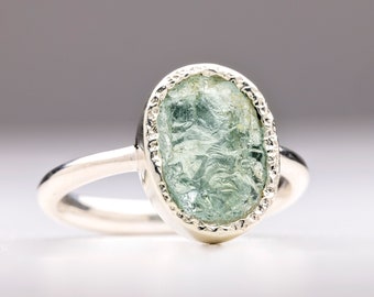 Op de afbeelding: Een zilveren ring met een lichtblauwe ovale aquamarijn, gezet in een zilveren bezel.