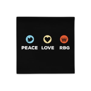 May include: Black pillow with the words "PEACE LOVE RBG" in white text. The words are separated by a blue bird, a yellow heart, and an orange crown. The pillow is square.