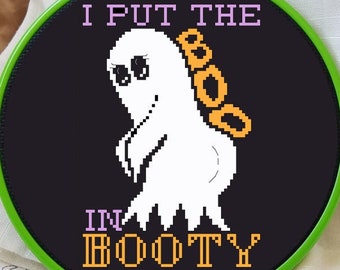 Puede incluir: Un aro de bordado verde con tela negra que presenta un fantasma blanco con letras naranjas "BOO" y el texto "I PUT THE BOO IN BOOTY".