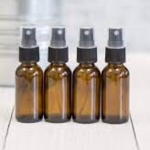 May include: Four amber glass bottles with black spray tops. The bottles are empty and lined up in a row.