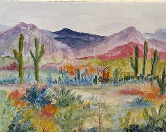 May include: Watercolor painting of a desert landscape featuring purple and red mountains, green cacti, and colorful foliage. The artwork depicts a serene scene with soft brushstrokes and a muted color palette, evoking a sense of the American Southwest.