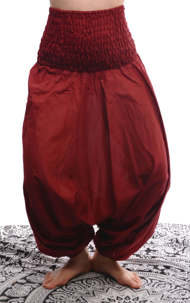 May include: A pair of loose-fitting, burgundy-colored pants with an elastic waistband. The pants are gathered at the ankles and have a flowing, relaxed fit.