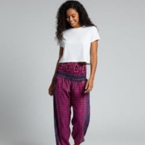 May include: A plain white short-sleeved t-shirt paired with loose-fitting magenta harem pants featuring a dark blue patterned waistband and intricate geometric designs in shades of purple and blue throughout the fabric of the pants.