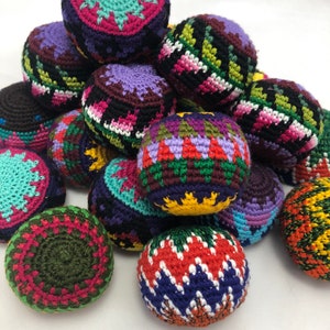Puede incluir: Una colección de coloridos sacos de hacky hechos a mano. Los sacos de hacky presentan varios patrones geométricos y combinaciones de colores, incluyendo turquesa, morado, verde y naranja. Cada bola mide aproximadamente 6,35 cm de diámetro.