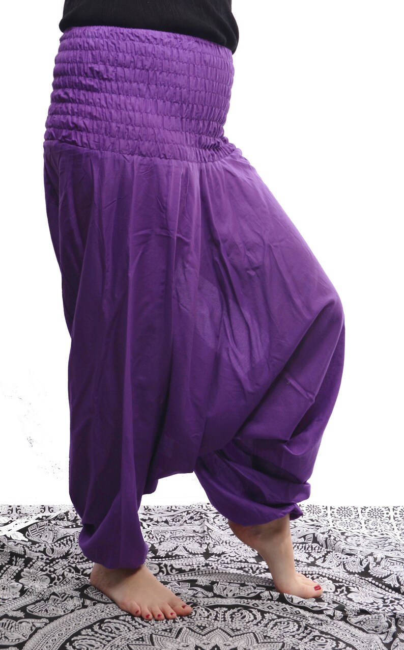 May include: Purple harem pants with a gathered elastic waistband. The pants are made of a soft, flowing fabric and have a wide, loose fit.