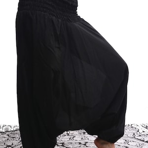 May include: Black harem pants with an elastic waistband. The pants are made of a soft, flowing fabric and have a wide, loose fit.