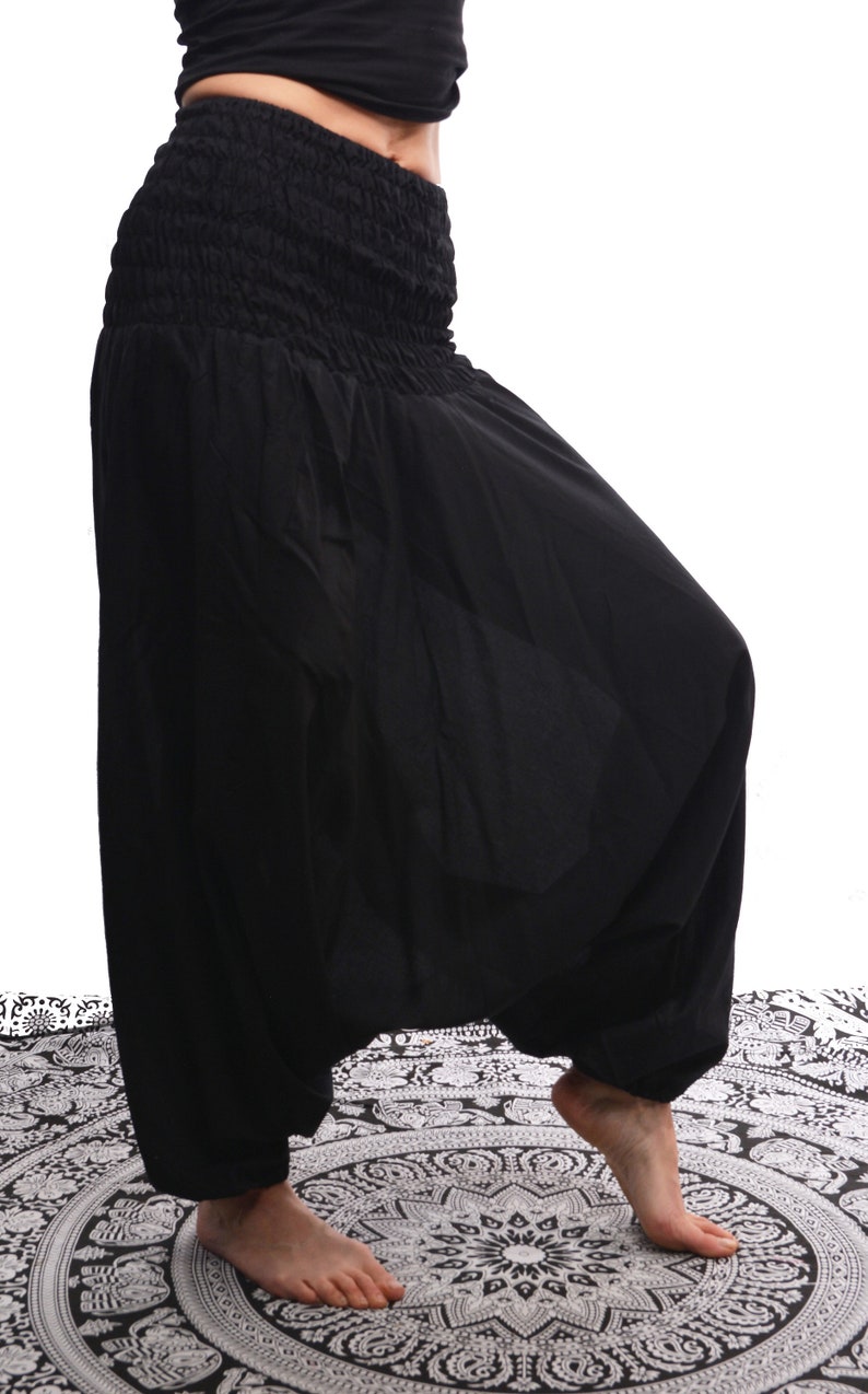 May include: Black harem pants with an elastic waistband. The pants are made of a soft, flowing fabric and have a wide, loose fit.