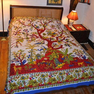 May include: A white cotton tapestry featuring a colourful tree of life design. The tree is red, yellow, green and blue with birds and animals throughout. The tapestry has a blue border.