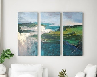 May include: A set of three abstract landscape paintings with a teal, green, and white color scheme. The paintings are framed and hung on a white wall above a white couch.
