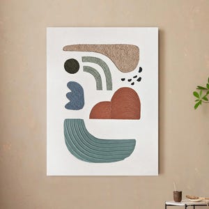 May include: A rectangular wall art piece featuring a white background with abstract shapes in beige, sage green, terracotta, and blue. The composition includes textured elements, curved lines, and small black dots arranged in a balanced, modern layout.