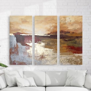 Może przedstawiać: Trójelementowy zestaw abstrakcyjnych wydruków artystycznych w kolorystyce złotej, brązowej i szarej. Wydruki przedstawiają krajobraz z linią horyzontu i fakturowanym efektem pociągnięć pędzla.