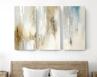 May include: A set of three abstract canvas wall art prints with a muted color palette of beige, brown, and blue. The prints feature a vertical brushstroke pattern.