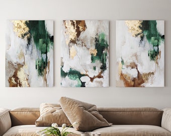 May include: Three abstract paintings in a set. The paintings are in shades of white, green, gold, and brown. The paintings are hung on a white wall above a brown couch.