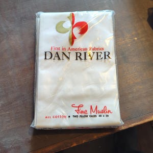 May include: A package of two white pillowcases made of 100% cotton. The package is labeled "Dan River Fine Muslin" and says "First in American Fabrics". The pillowcases are 42 inches by 36 inches.