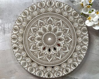 May include: A silver and white mandala wall art with a circular design. The mandala is made of intricate patterns and details.