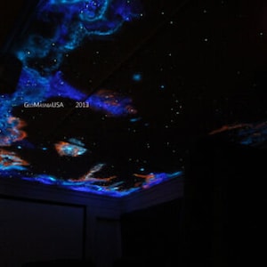 May include: A dark ceiling painted with a glow-in-the-dark galaxy scene. The ceiling features blue, orange, and white clouds with a scattering of stars. The text "GlowMagicUSA 2013" is visible in the upper center of the image.