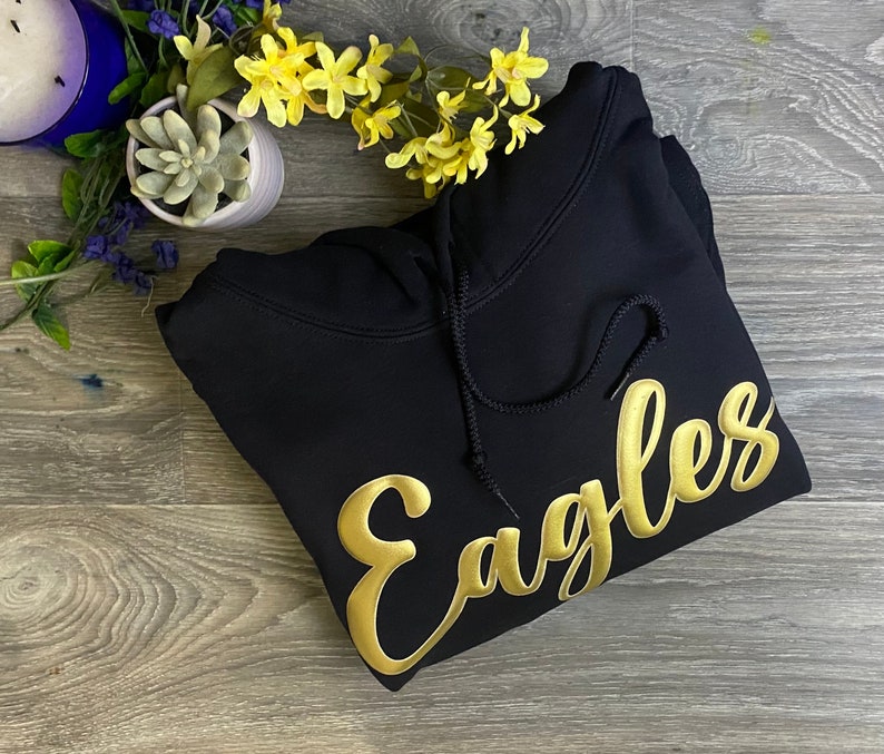 May include: Black hooded sweatshirt with a gold embroidered "Eagles" design.