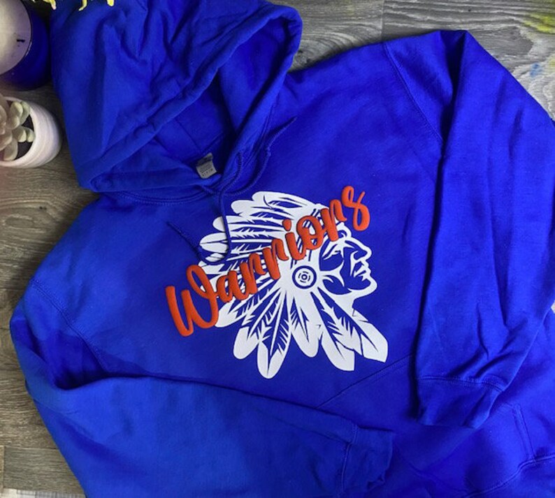 May include: A royal blue hooded sweatshirt with a white and red graphic of a Native American headdress and the word "Warriors" in red.