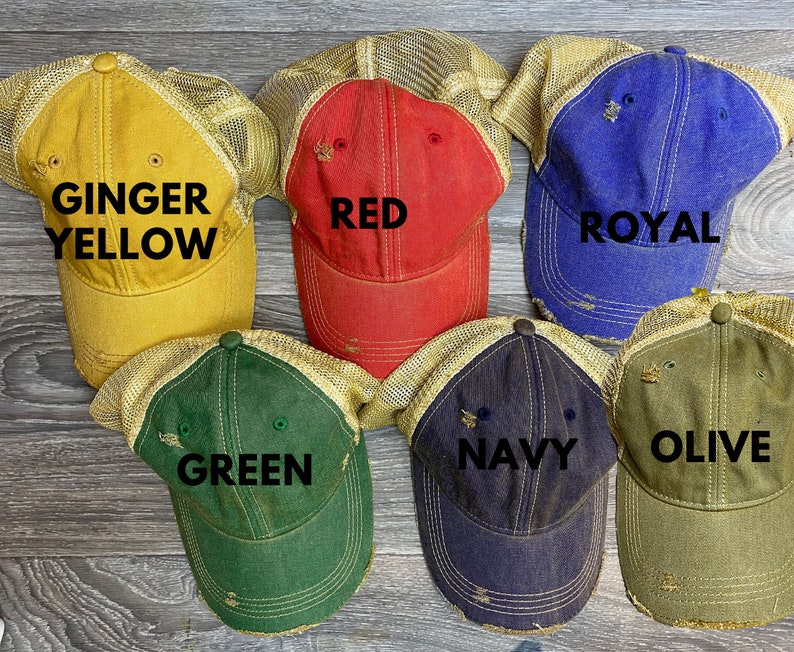 May include: Six different colored trucker hats with mesh back panels. The hats are labeled with the colors: Ginger Yellow, Red, Royal, Green, Navy, and Olive.